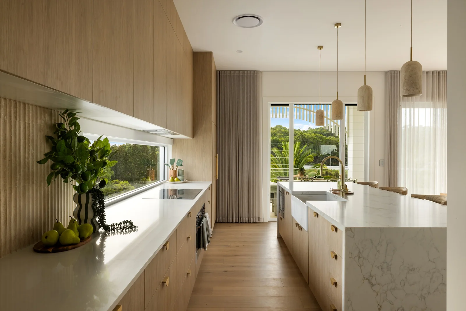 Oak cabinetry and a pale stone kitchen island opening onto the living area