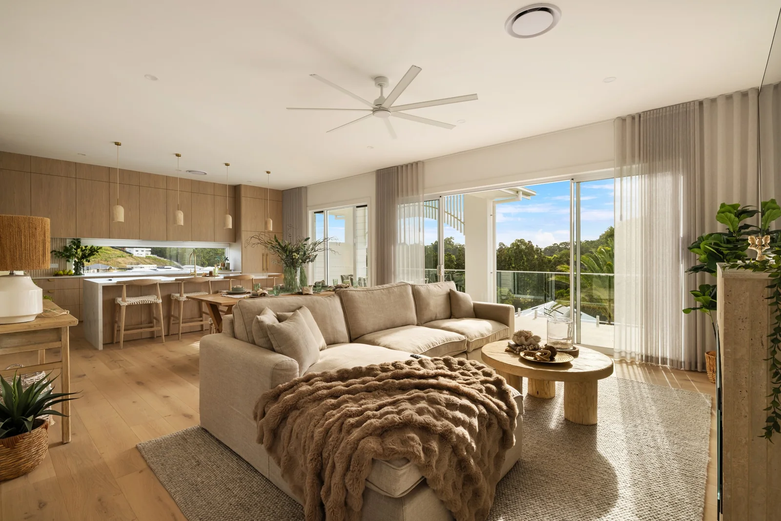 Open-plan living room with curved sofas, oak furniture and views towards the palms